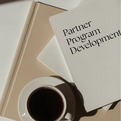 Coffee cup beside books featuring "Partner Program Development," symbolizing strategic advisory and business growth.