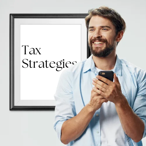 Smiling man holding smartphone in front of framed sign displaying "Tax Strategies," reflecting Sanguine Strategic Advisors' focus on tailored business solutions and financial growth.