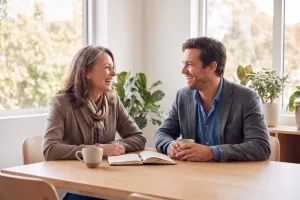 Two long-standing business contacts talking warmly over coffee at a sunlit table